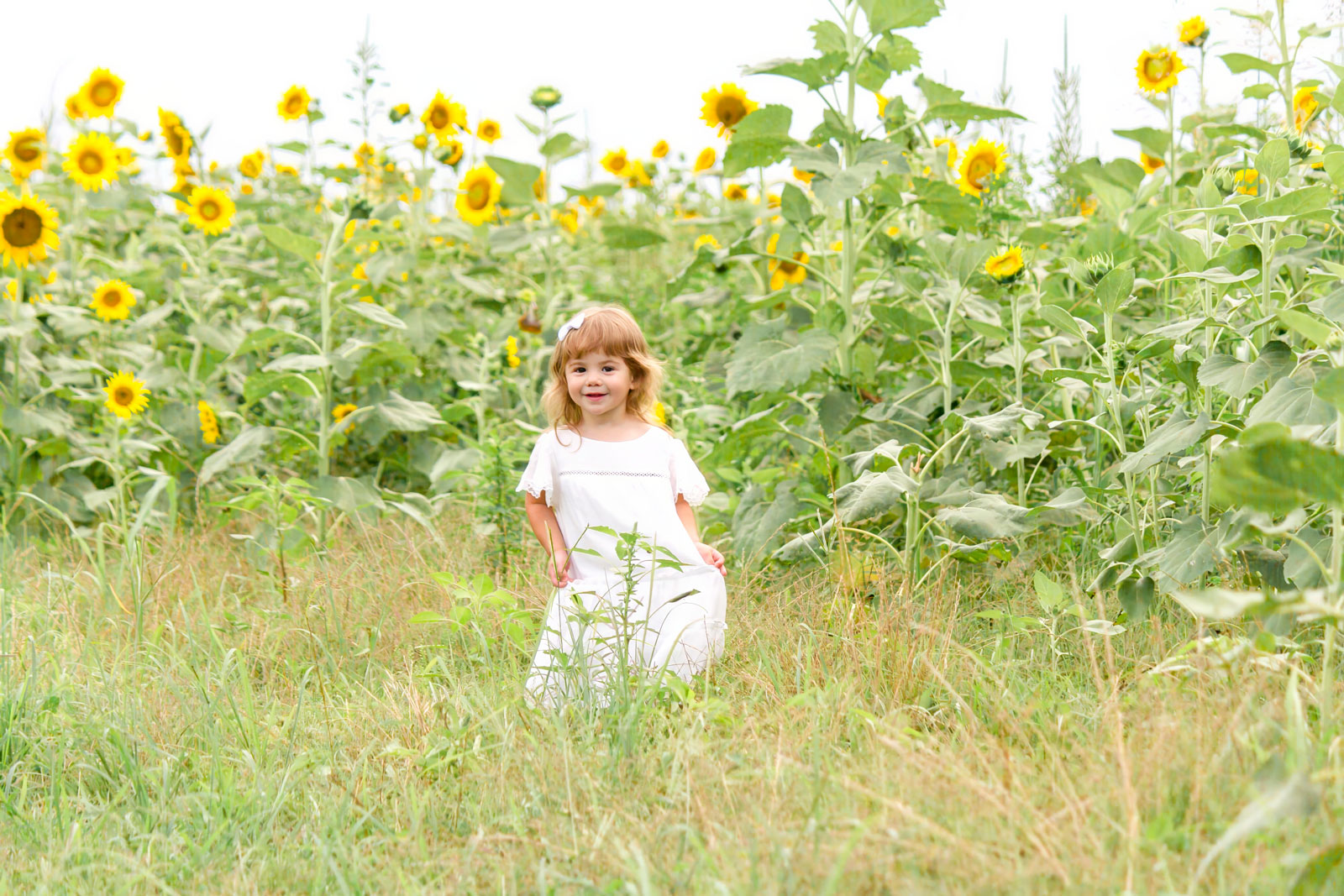 little girl swinging her dress by the sunflowers at the sunflower field in Belcher, LA