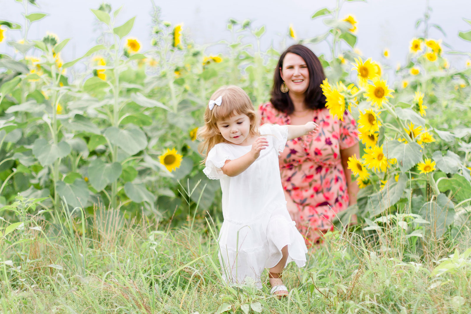 little girl running away from her mom by the sunflowers at the sunflower field in Belcher, LA