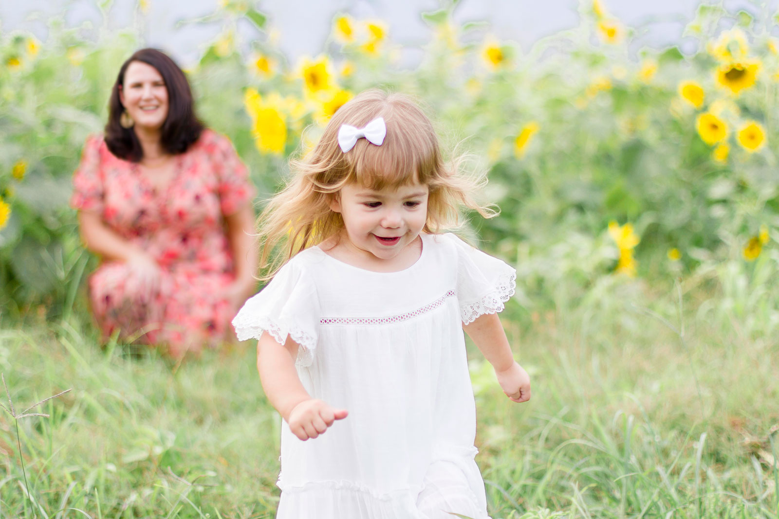 little girl running away from her mom by the sunflowers at the sunflower field in Belcher, LA