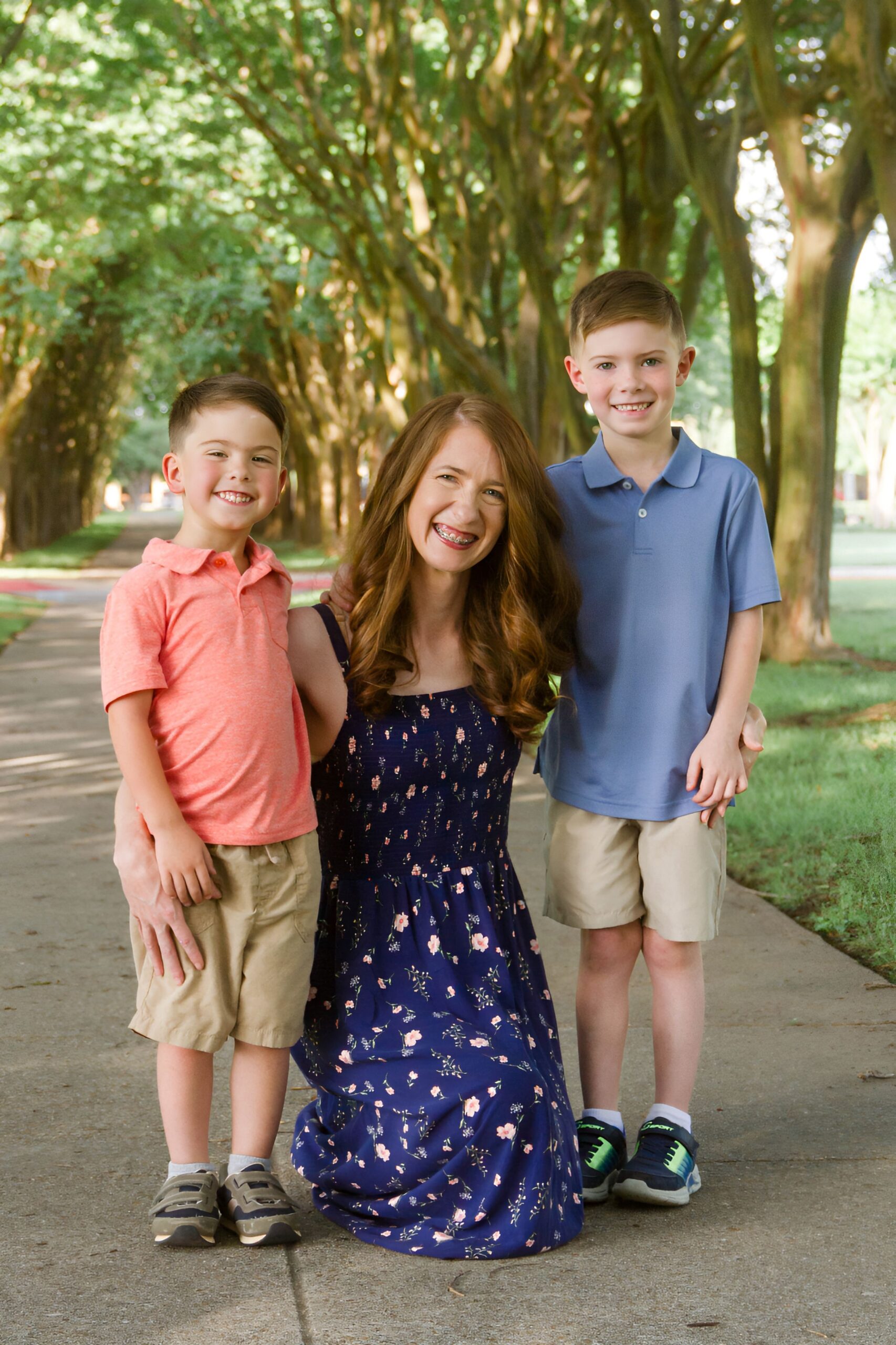 mom in between her two sons on a pathway between trees outdoor for a family session in Shreveport LA