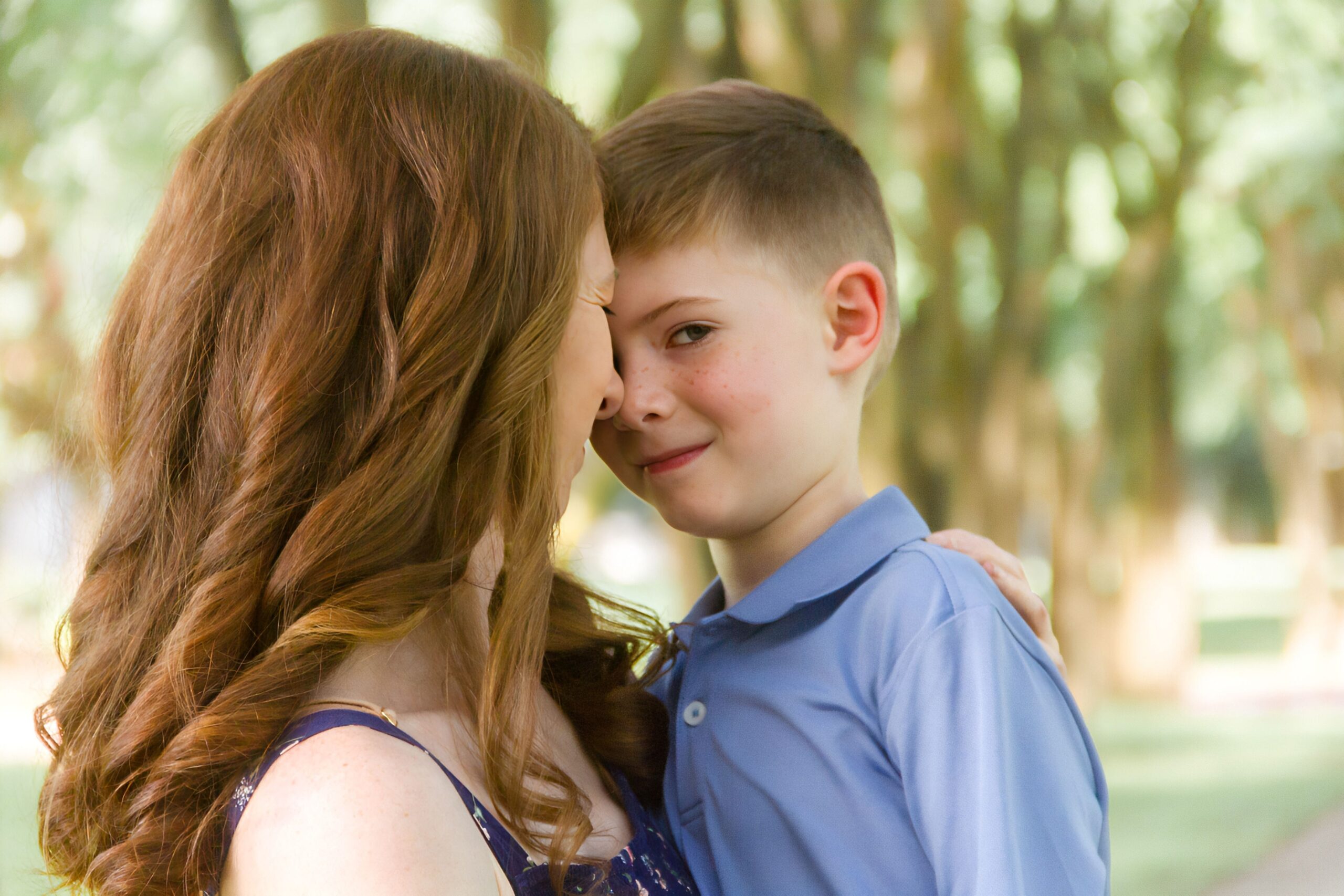 mom give her son noses on a pathway between trees outdoor for a family session in Shreveport LA