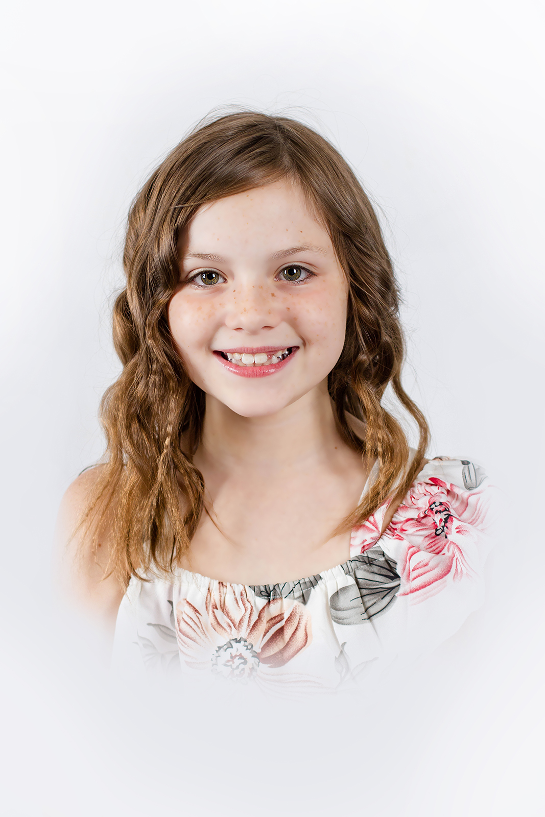 little girl dressed in floral smiling inside studio for a heirloom portrait