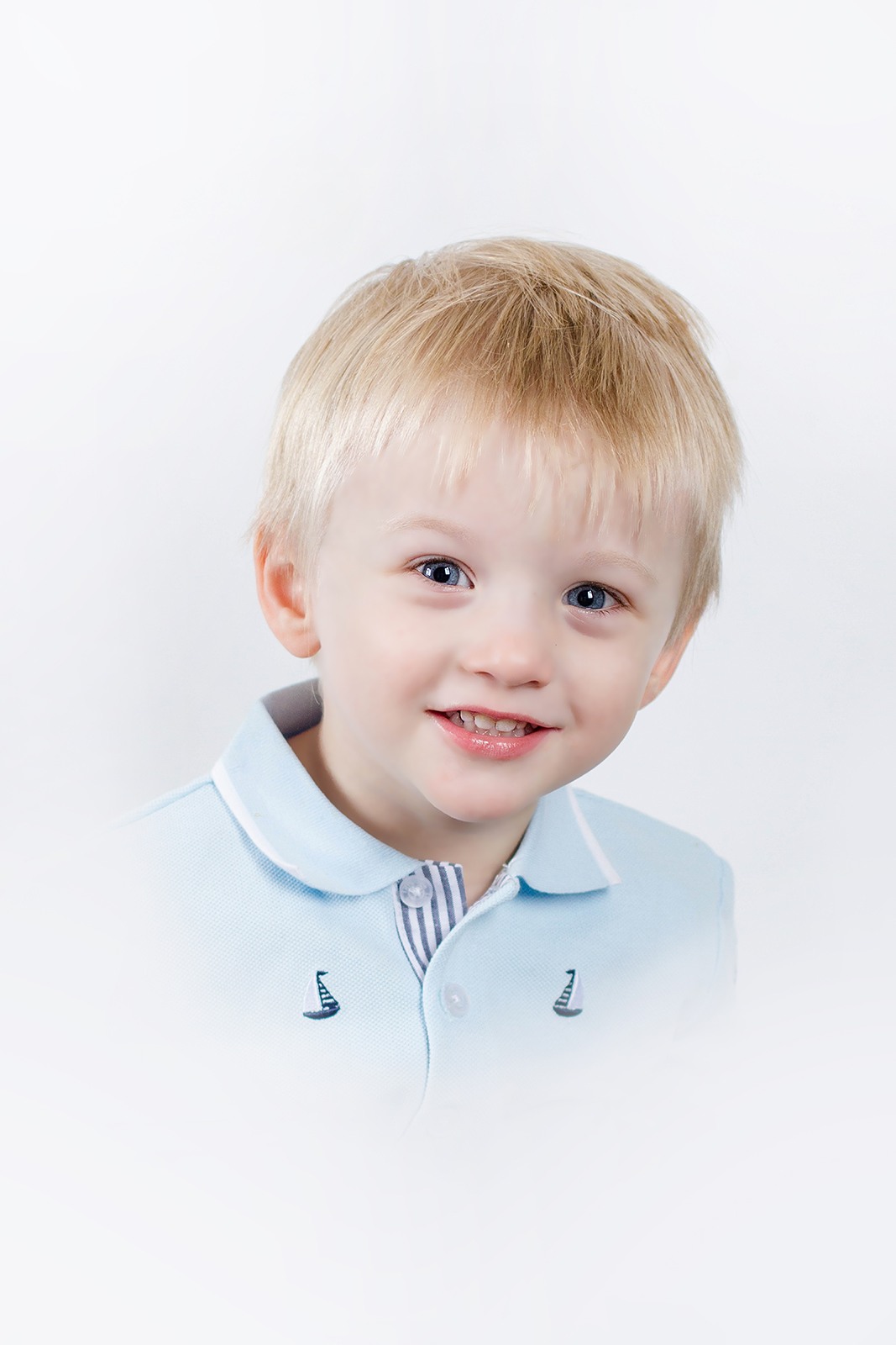 little toddler boy dressed in blue sailboat shirt smiling inside studio for a heirloom portrait