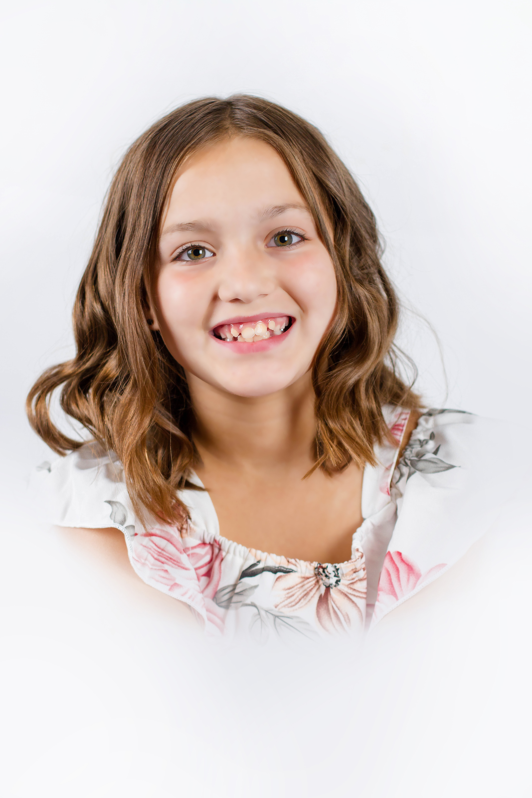 little girl dressed in floral smiling inside studio for a heirloom portrait