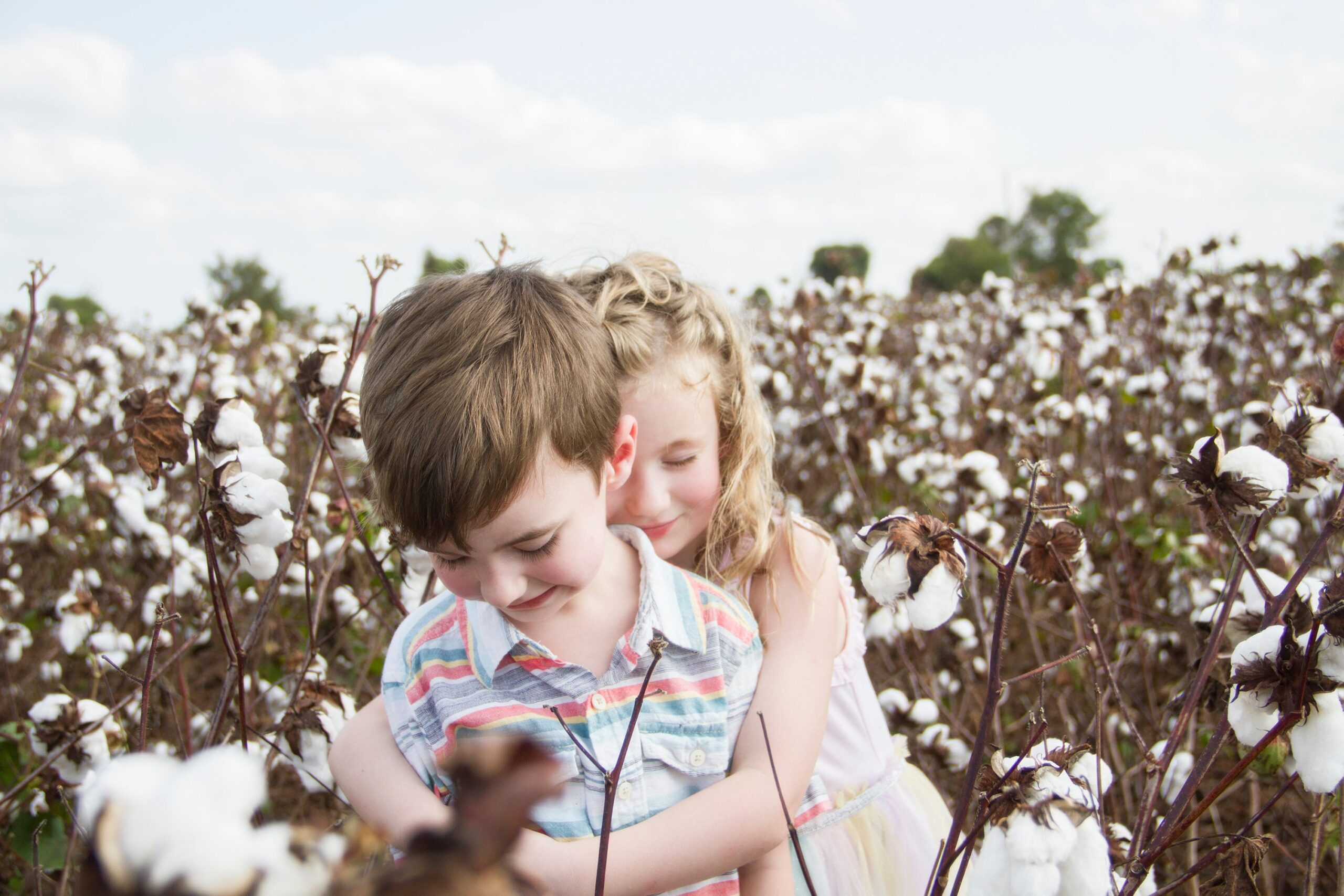 little sister hugging little brother from behind at the cotton field in belcher, la