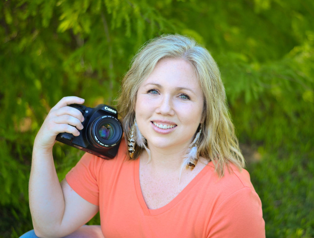 woman smiling at the camera while holding a canon camera in Benton, Louisiana