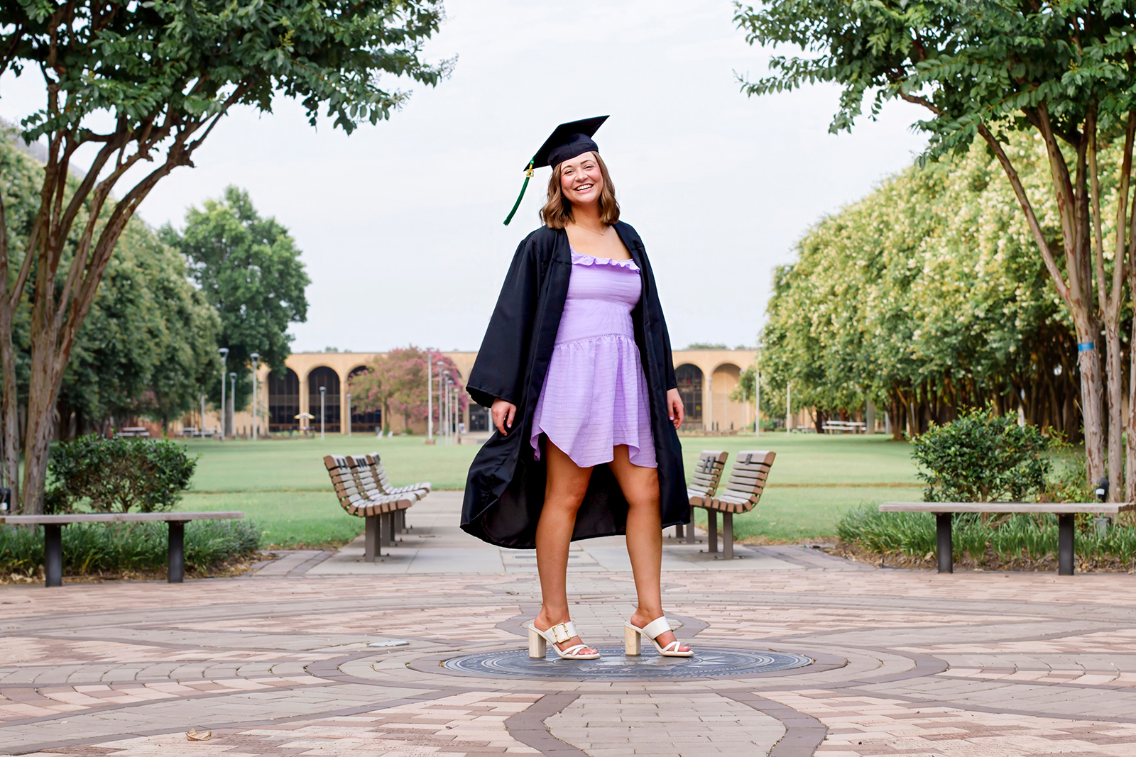 college grad med senior wearing black cap and gown while standing proudly on LSUS campus Shreveport LA