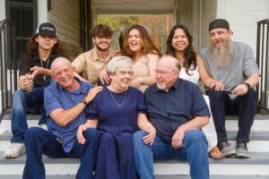 Family laughing on white porch steps at the Hughes House in Benton, LA