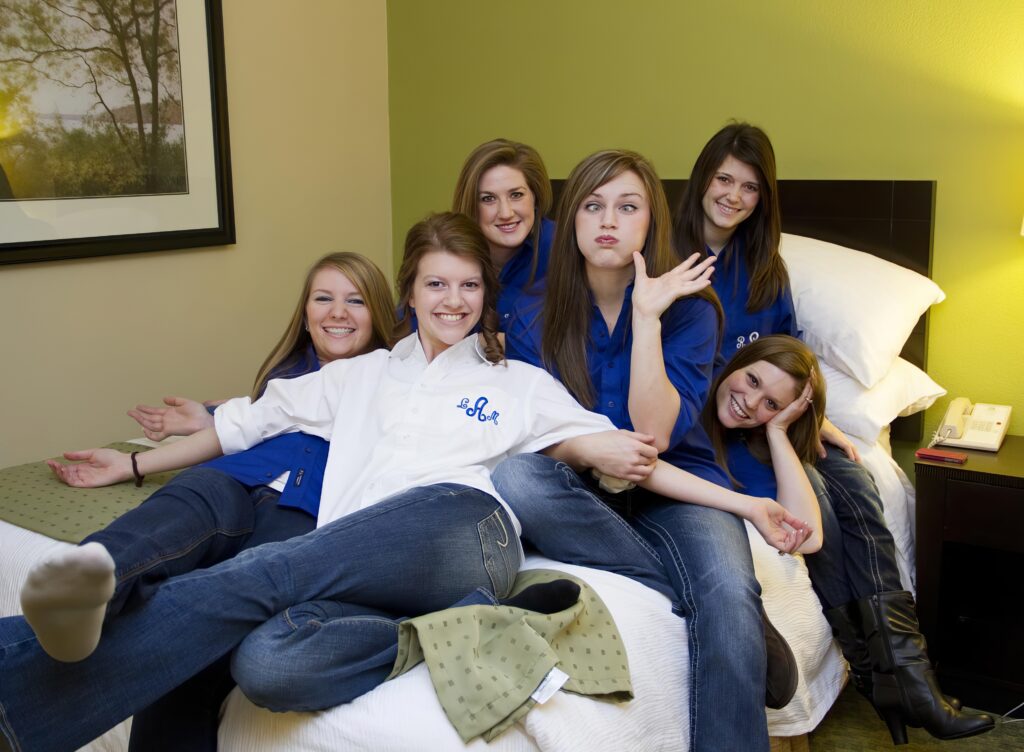 bride with bridemaids on the bed in a hotel smiling and having fun in Shreveport, LA