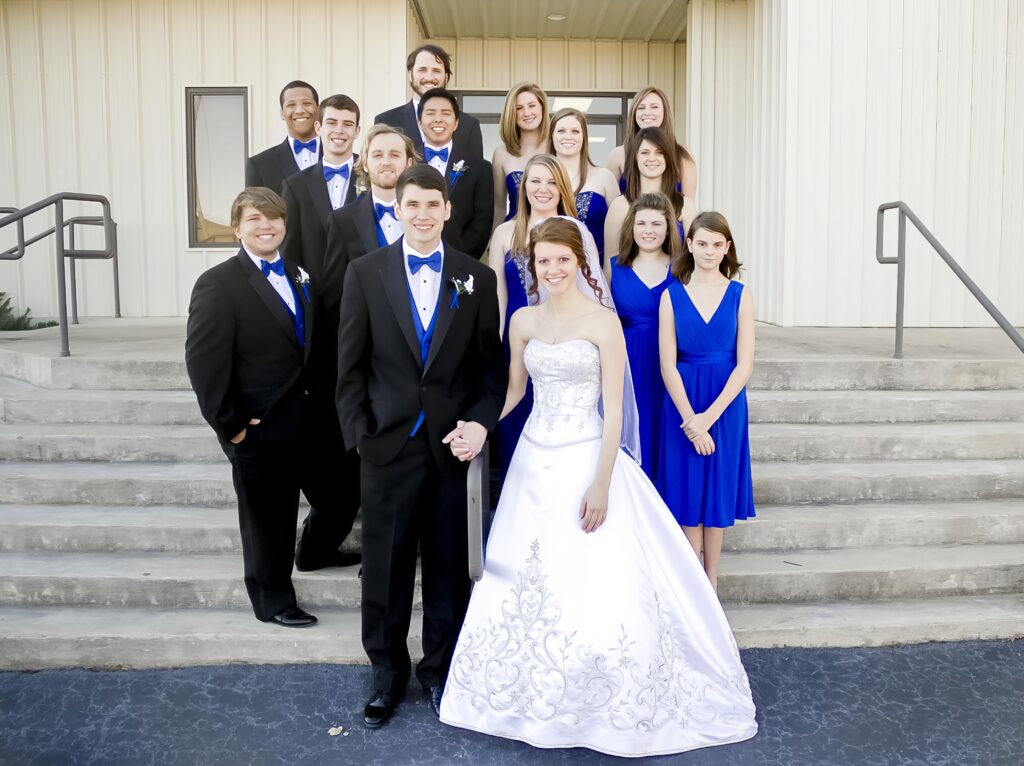 groom and bride standing on the stair case at Rose Park Baptist with the bridal party in Shreveport, LA