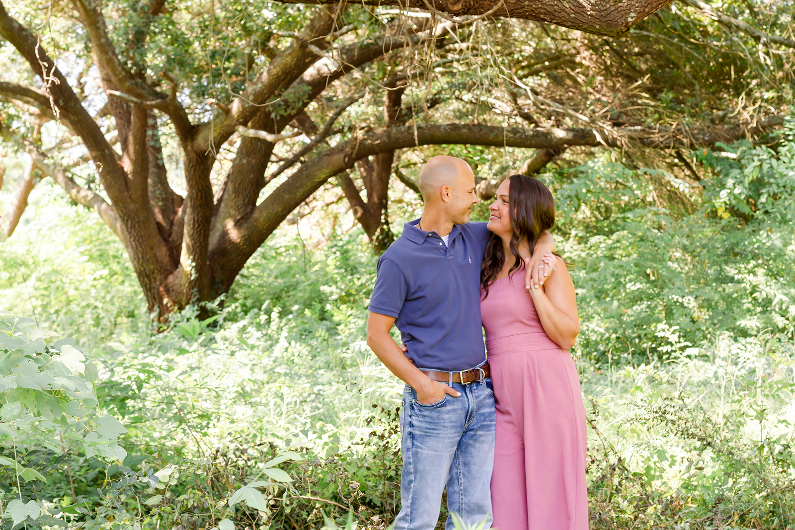 man wrapped arm around woman while smiling at each other in Shreveport, LA field of grass