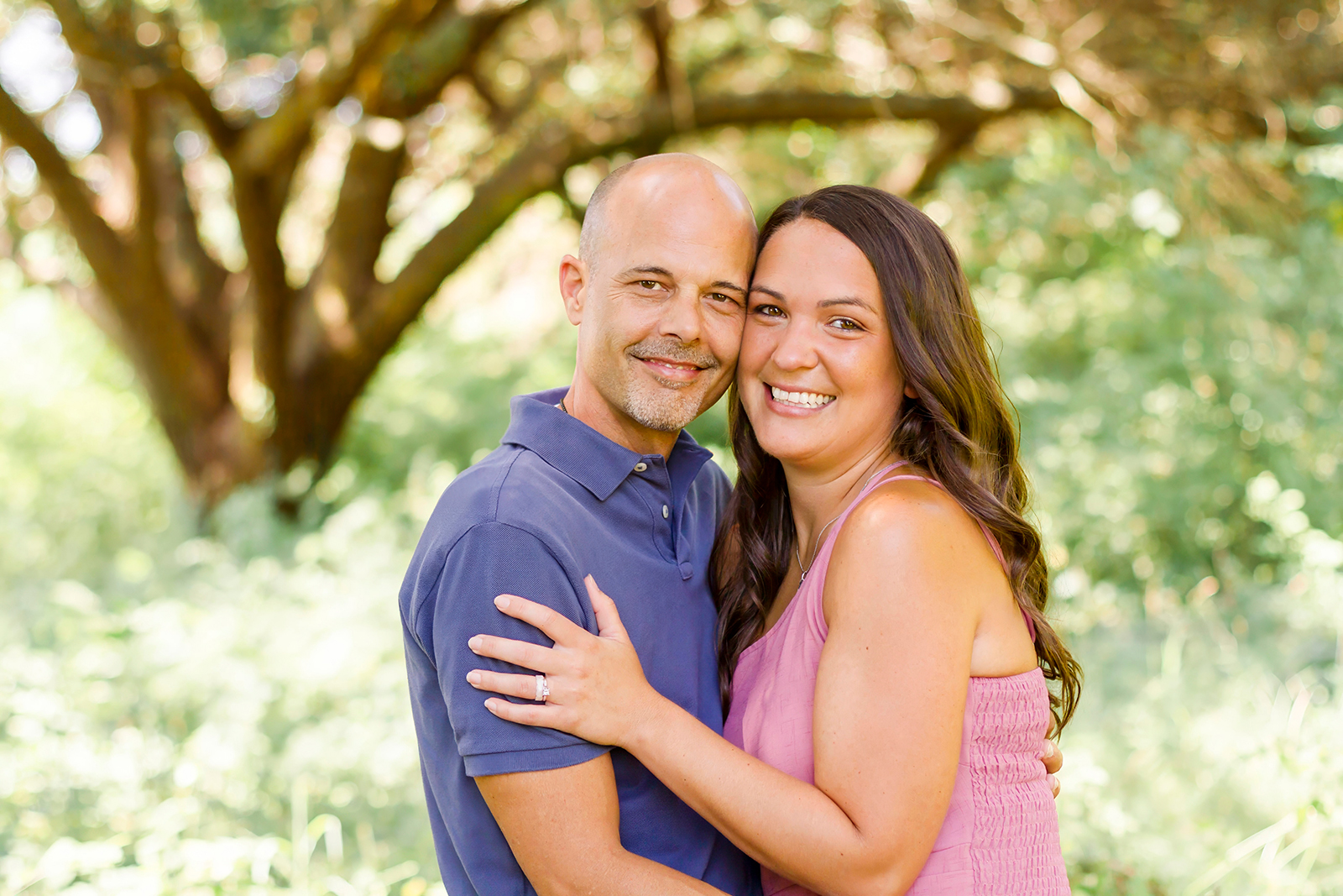 man and woman smiling asa. couple in Shreveport, LA field of grass