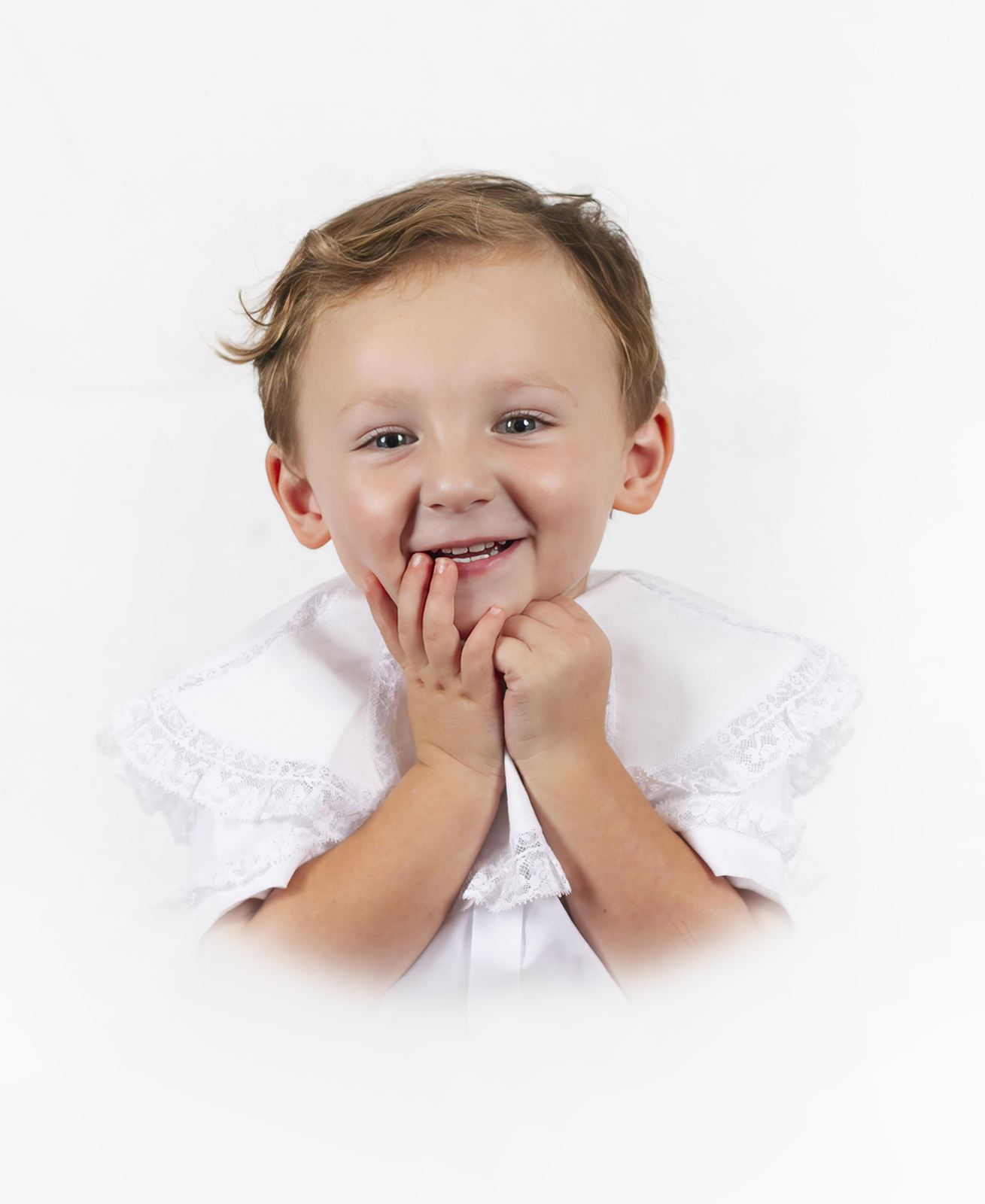 little boy toddler smiling at the camera with his hands on his face during a heirloom portrait home studio session in bossier city, la