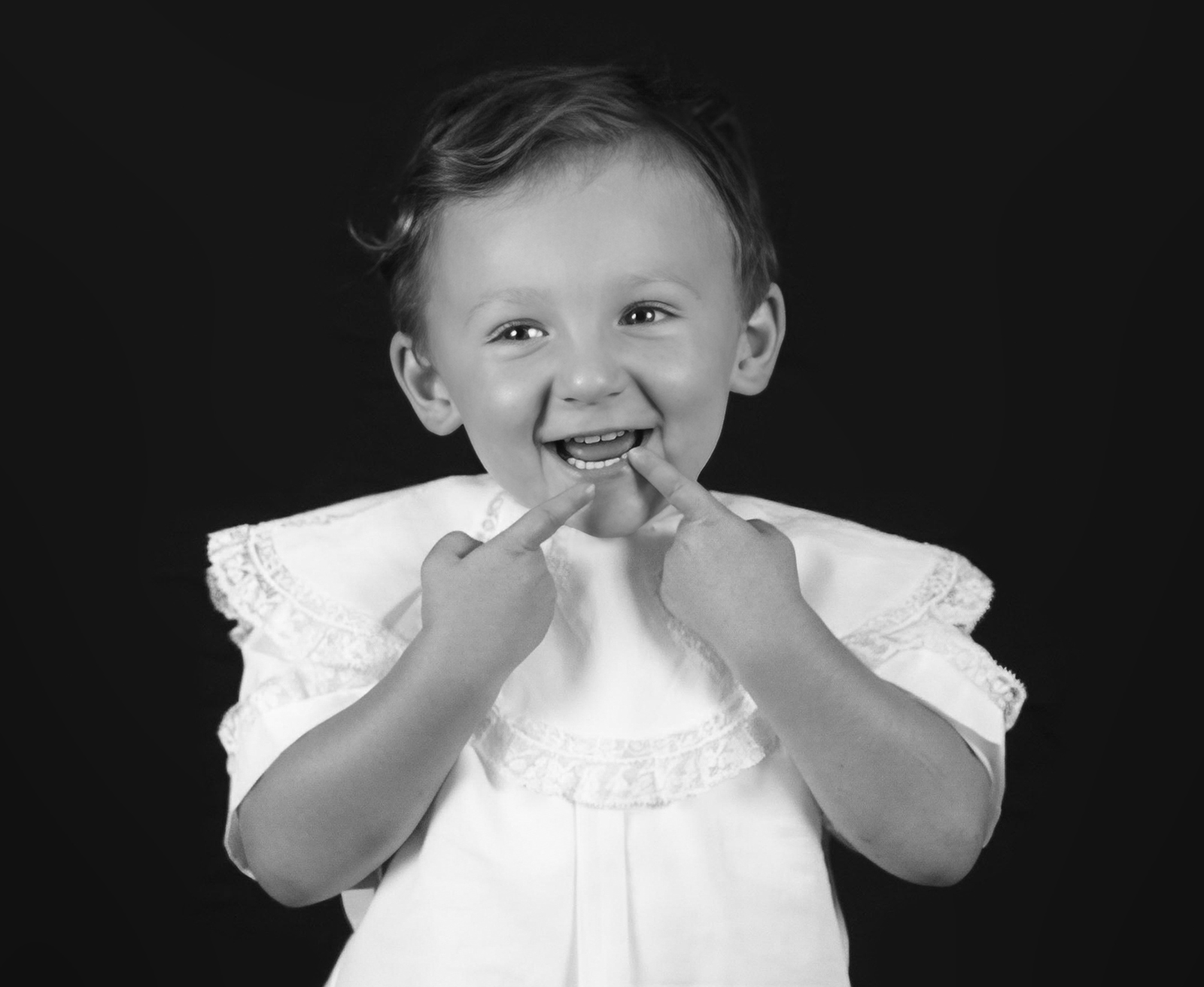 little boy toddler with his fingers on his lips smiling during personality portrait home studio session in bossier city, la