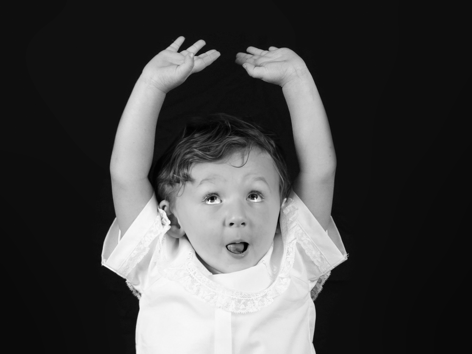 little boy toddler with his hands up in the air making a silly face during personality portrait home studio session in bossier city, la