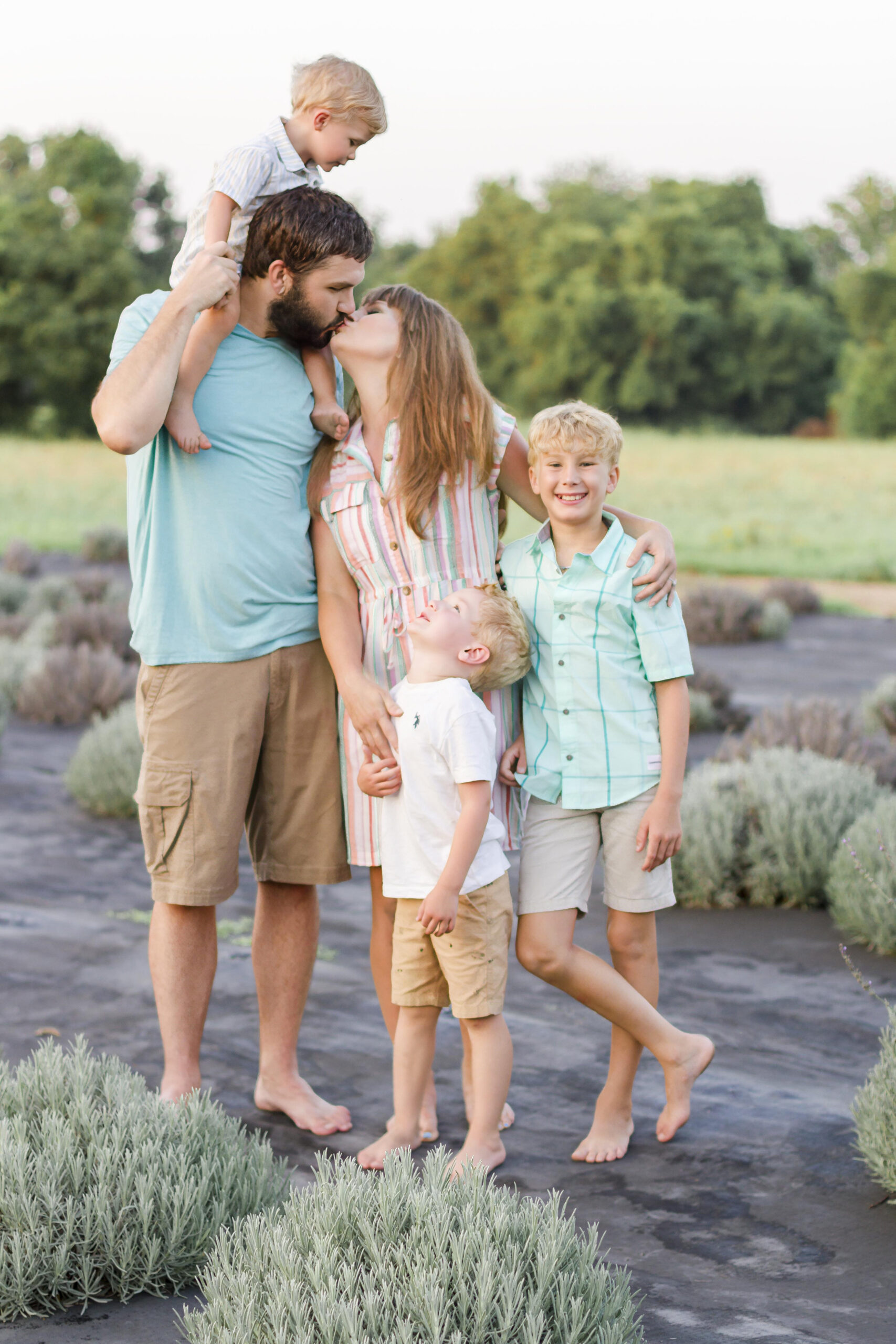 mom and dad kissing while kids are smiling and looking at the Dixie Farm Lavender in Shreveport, LA