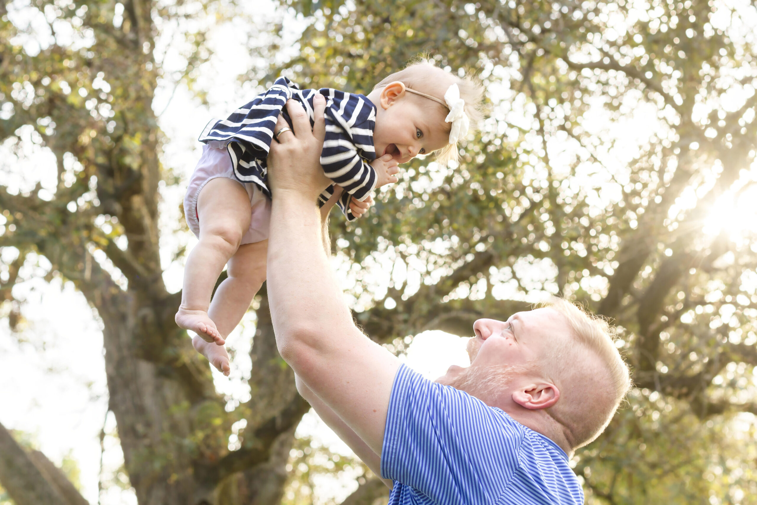 dad holding baby girl high in the sky in Bossier City, la at Red River Wildlife Refuge Center