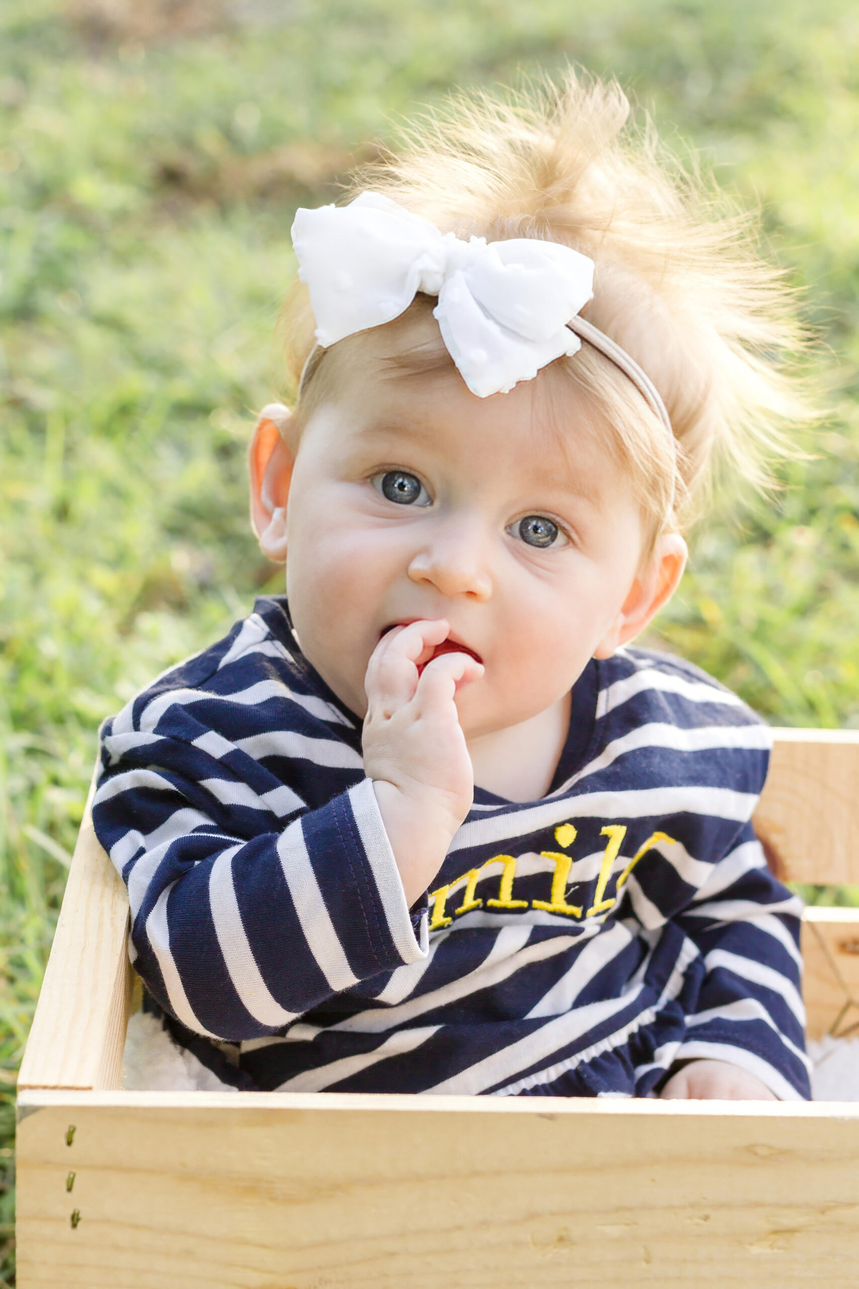 little baby girl sitting in a wooden crate on the ground in Bossier City, la at Red River Wildlife Refuge Center