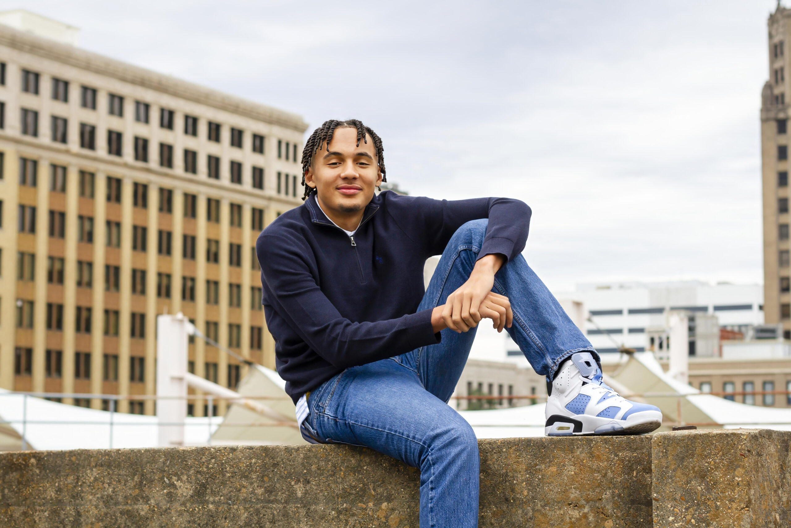 Senior boy sitting on concrete wall in downtown Shreveport, LA