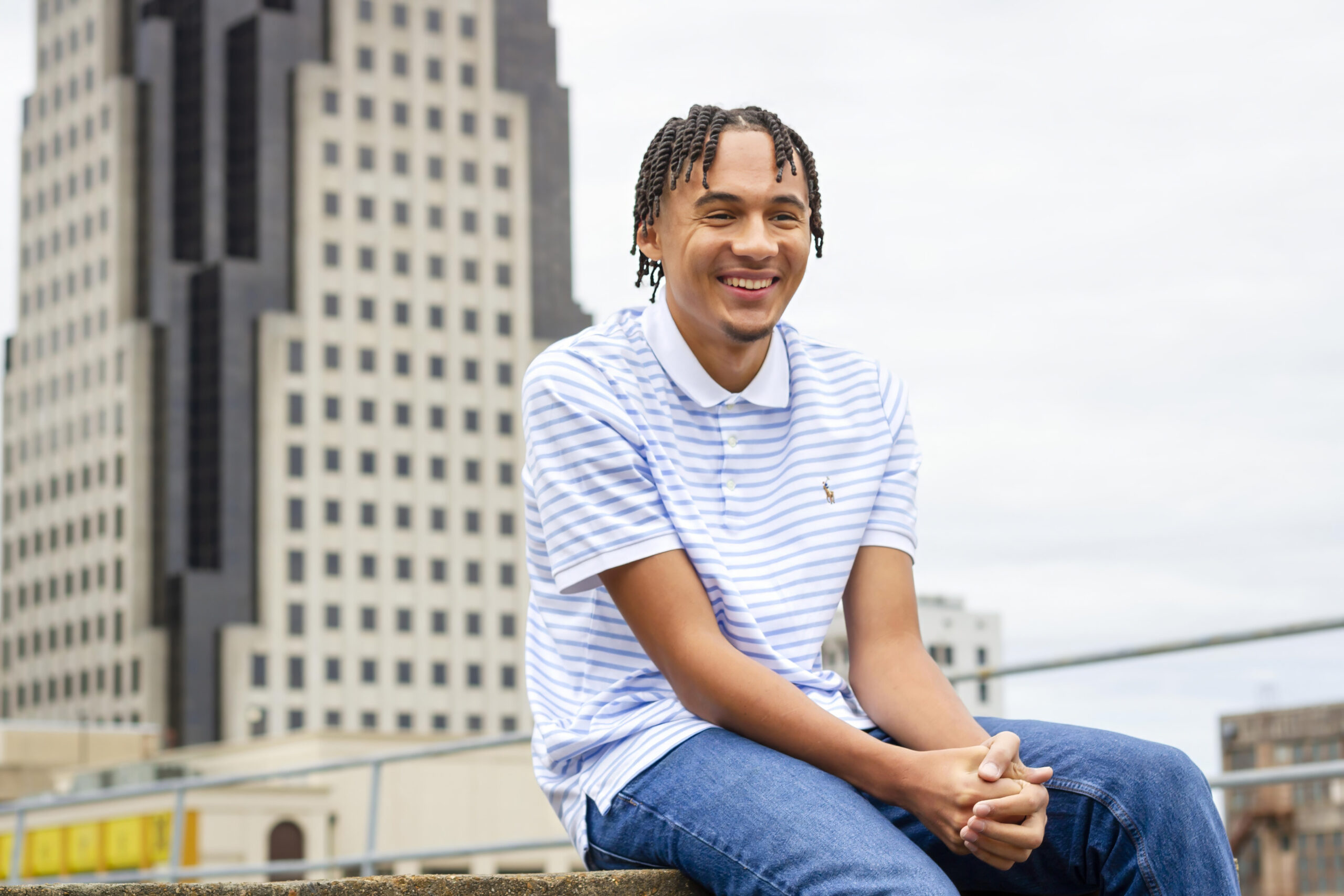 senior boy smiling and laughing while sitting on concrete on an empty parking garage in downtown Shreveport, LA