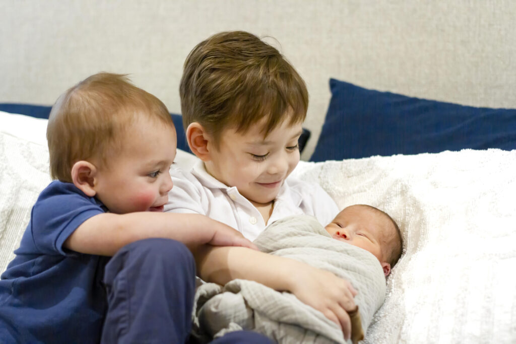 two older brothers holding their newborn baby brother in his house in Bossier City, LA