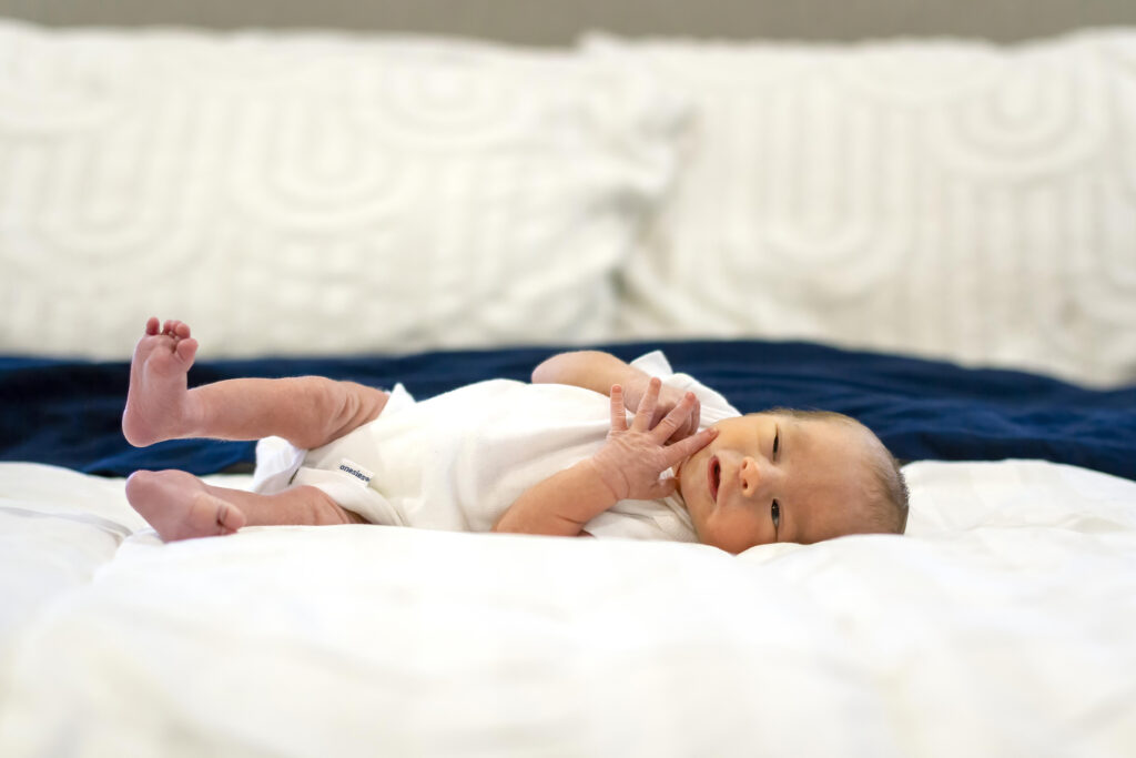 newborn baby boy laying down on his parent's bed in his house in Bossier City, LA